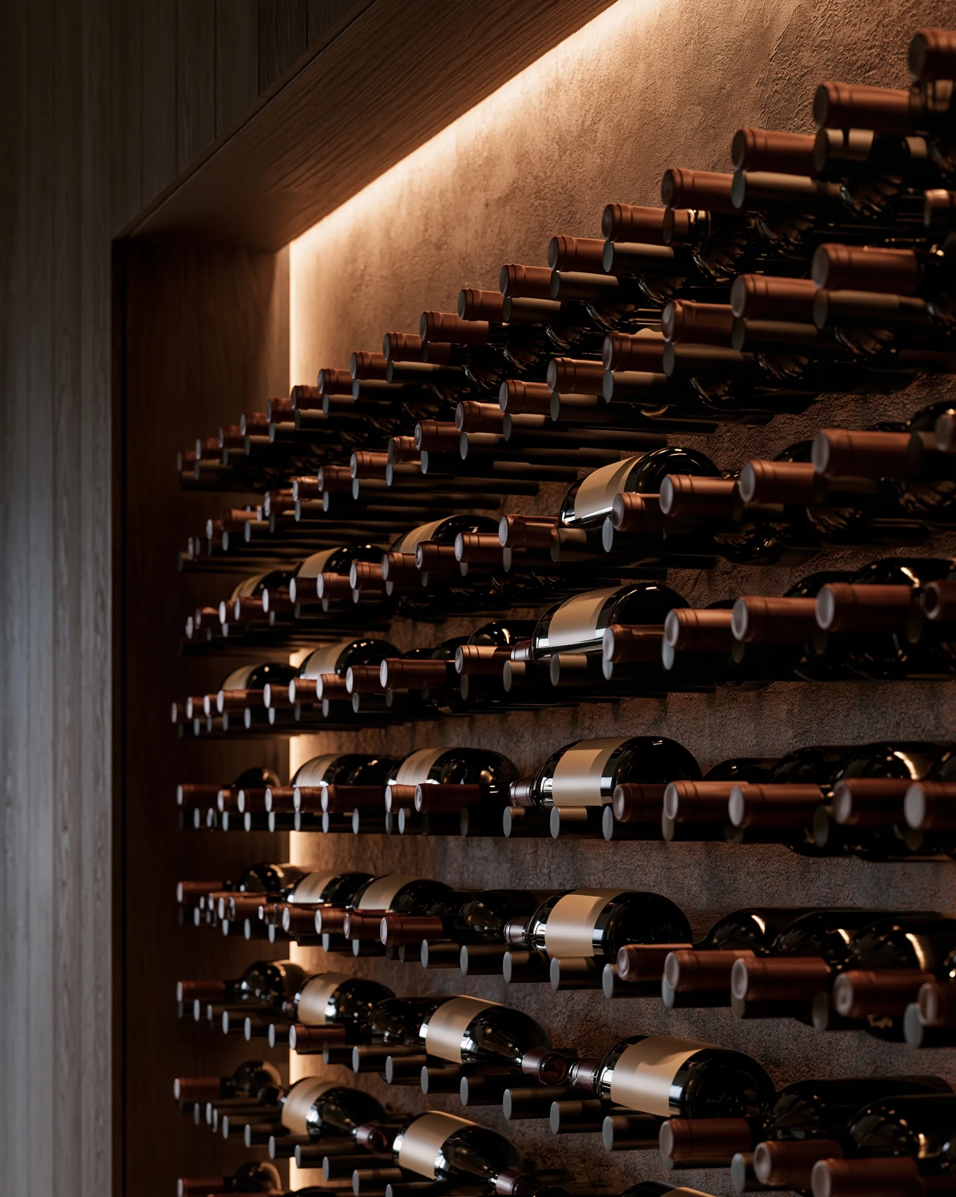 Wine bottles held label-out on rows of metal pegs across a plaster wall, inside a wood-framed niche lit along the top